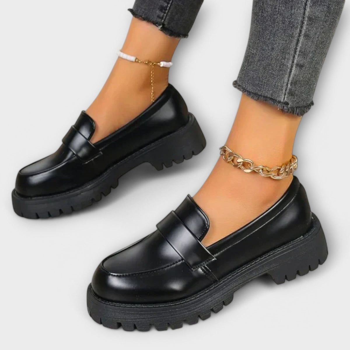 Black chunky-soled loafers worn with an ankle chain